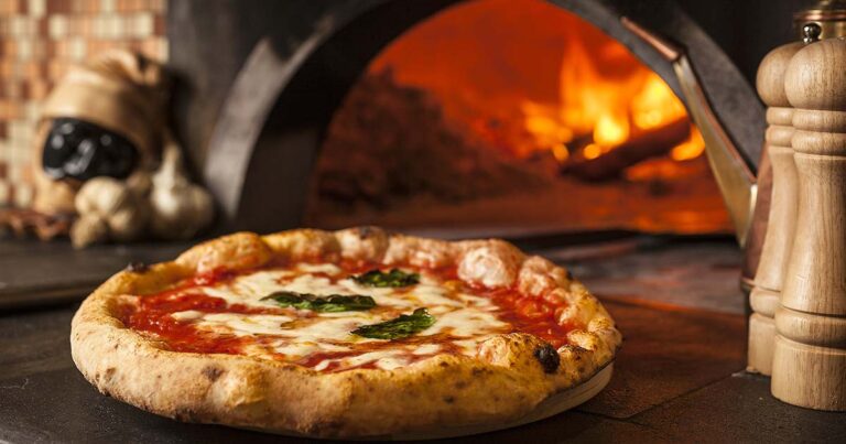 Pizza napolitaine fraîchement cuite, sortie d'un four à pizza traditionnel, montrant l'aboutissement de la formation.