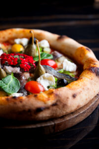 Pizza contemporaine avec capres et fleurs comestibles