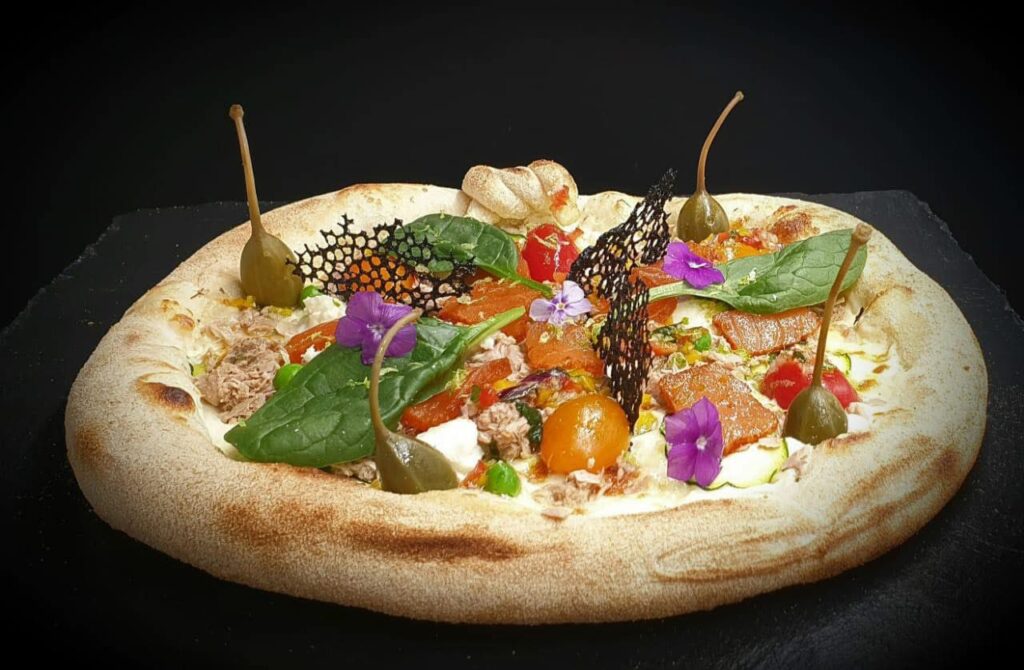 Pizza CQP Pizzaiolo, garnie de tomates, câpres, basilic et fleurs comestibles, préparée lors de la formation.